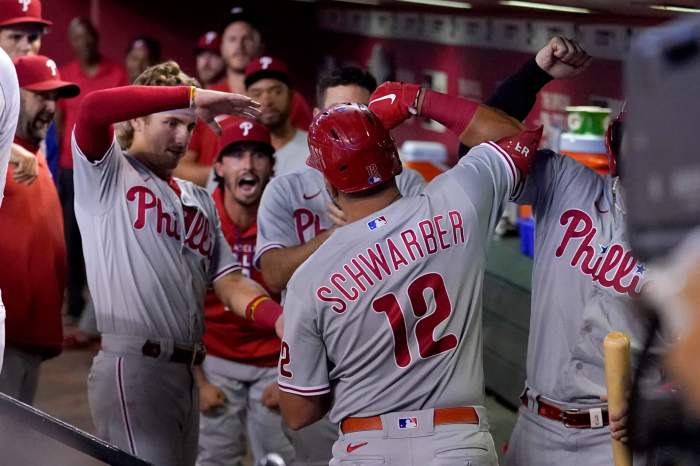 Philadelphia Phillies' Kyle Schwarber (12) is greeted in the dugout by teammates after hitting a three run home run against the Arizona Diamondbacks during the fourth inning of a baseball game, Monday, Aug. 29, 2022, in Phoenix. (AP Photo/Matt York)